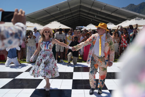 man and women in bold floral outfits as best dressed competition winners in front of crowd