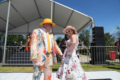man and women in bold floral outfits as best dressed competition winners with stage in background