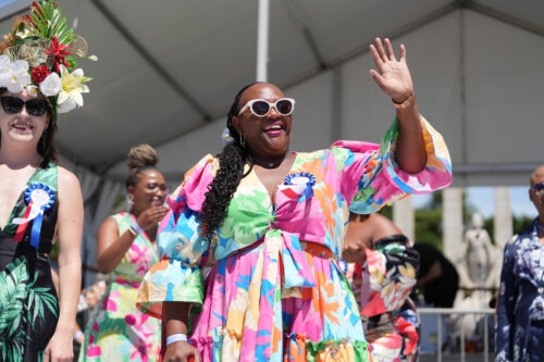 best dressed competition winner in pink and pastel colored dress waving at crowd